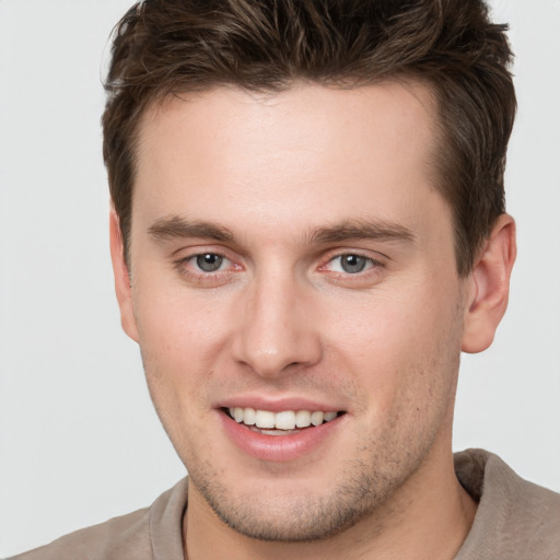 Joyful white young-adult male with short  brown hair and grey eyes