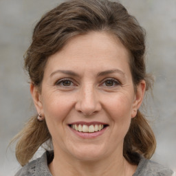 Joyful white adult female with medium  brown hair and grey eyes