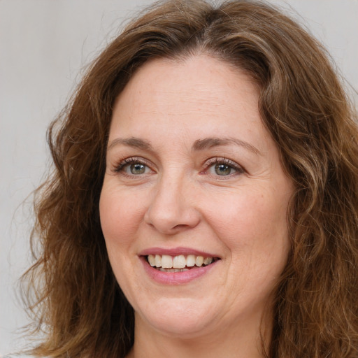 Joyful white adult female with long  brown hair and green eyes