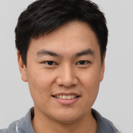 Joyful asian young-adult male with short  brown hair and brown eyes