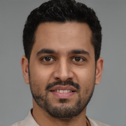 Joyful latino young-adult male with short  black hair and brown eyes