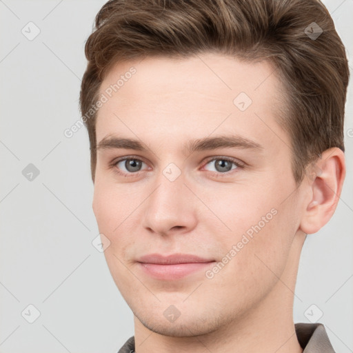 Joyful white young-adult male with short  brown hair and grey eyes