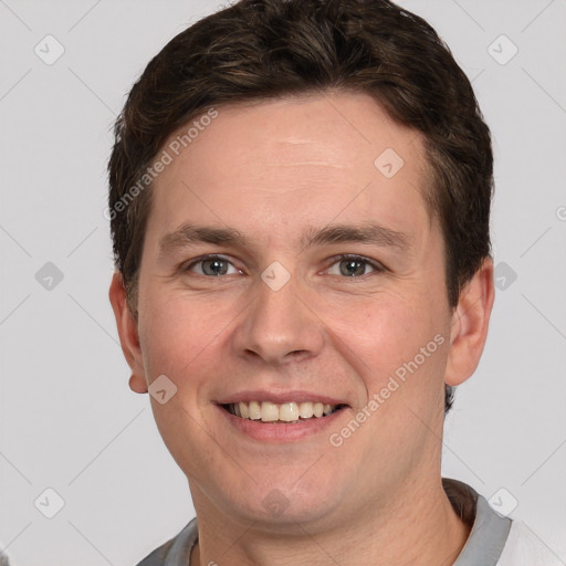 Joyful white young-adult male with short  brown hair and grey eyes