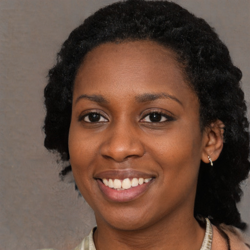 Joyful black young-adult female with long  black hair and brown eyes