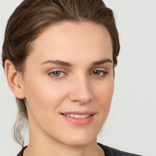 Joyful white young-adult female with medium  brown hair and grey eyes