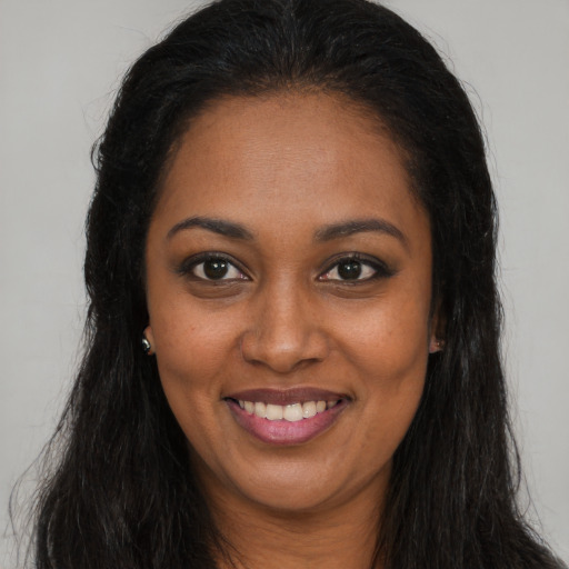 Joyful black young-adult female with long  brown hair and brown eyes