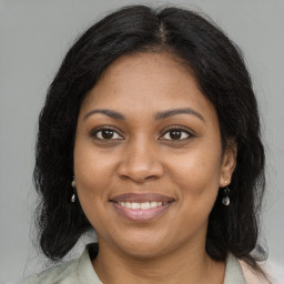 Joyful black young-adult female with long  brown hair and brown eyes