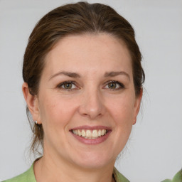 Joyful white young-adult female with medium  brown hair and green eyes