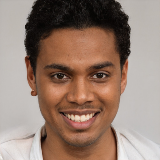 Joyful black young-adult male with short  brown hair and brown eyes