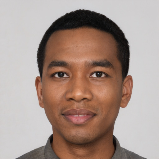 Joyful black young-adult male with short  black hair and brown eyes