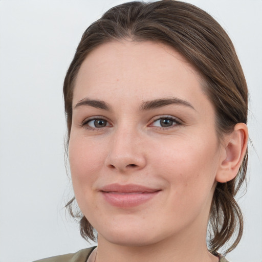 Joyful white young-adult female with medium  brown hair and grey eyes