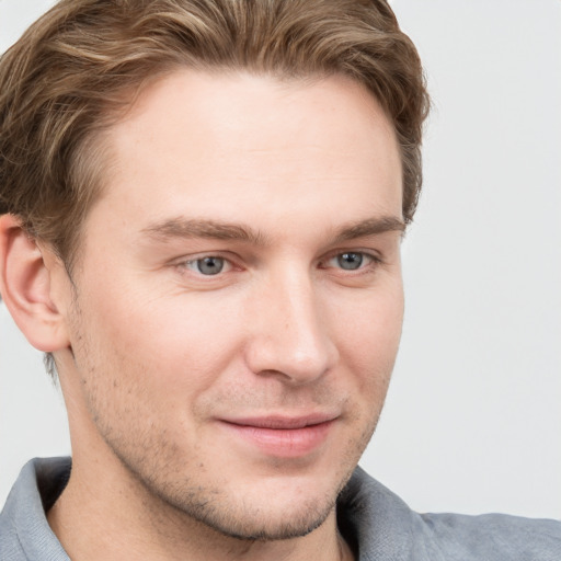 Joyful white young-adult male with short  brown hair and grey eyes