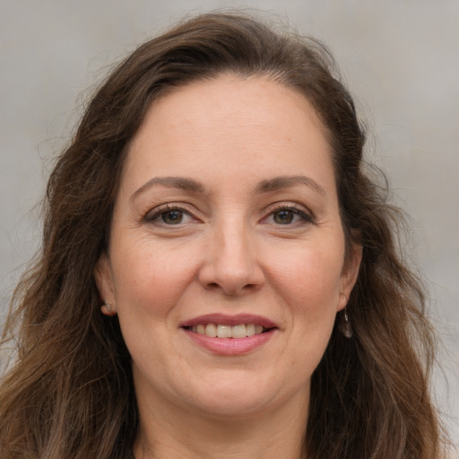 Joyful white adult female with long  brown hair and grey eyes