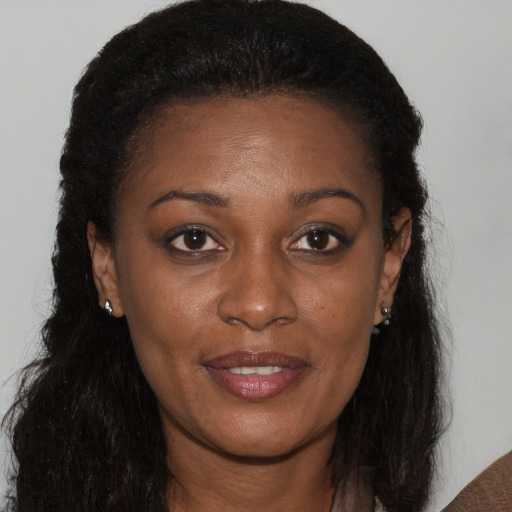 Joyful black young-adult female with long  brown hair and brown eyes