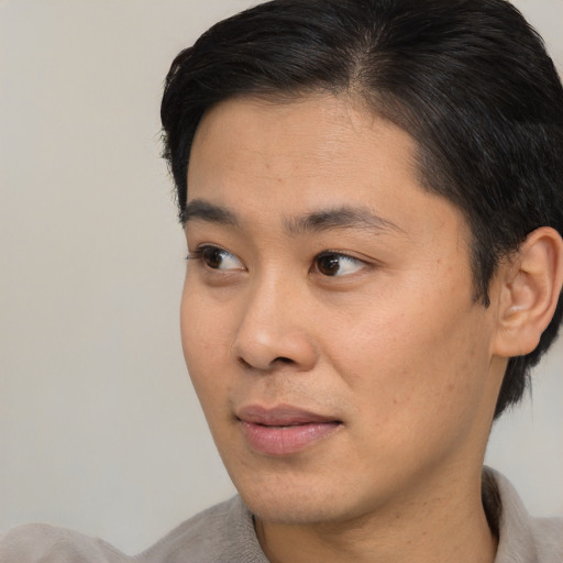 Joyful asian young-adult male with short  black hair and brown eyes