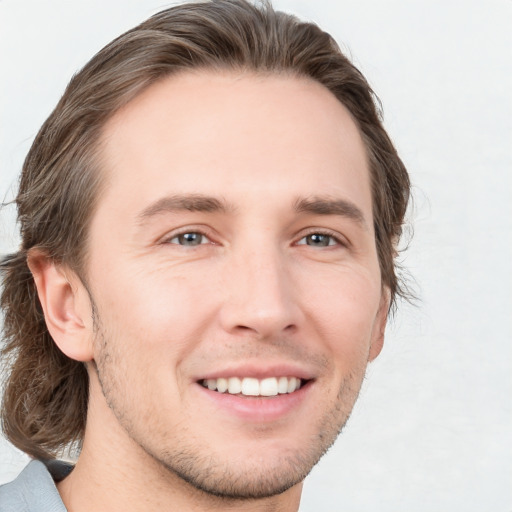 Joyful white young-adult male with medium  brown hair and grey eyes