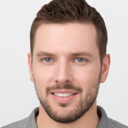 Joyful white young-adult male with short  brown hair and grey eyes