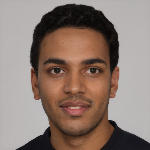 Joyful black young-adult male with short  black hair and brown eyes