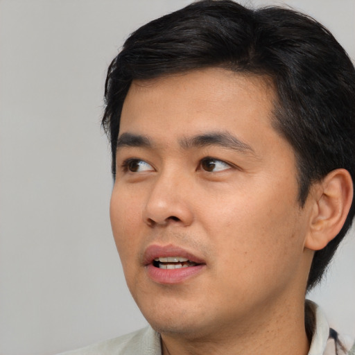 Joyful asian young-adult male with short  black hair and brown eyes