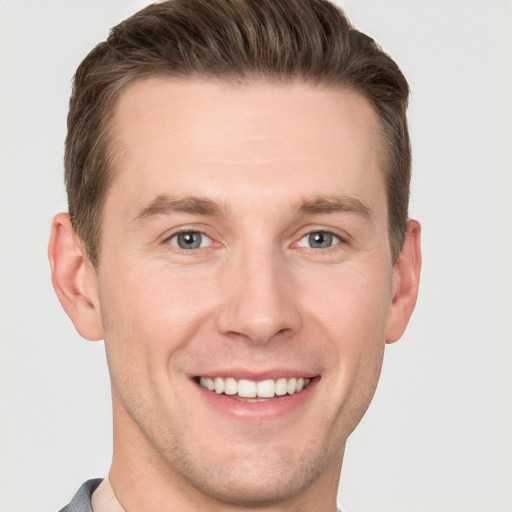 Joyful white young-adult male with short  brown hair and grey eyes