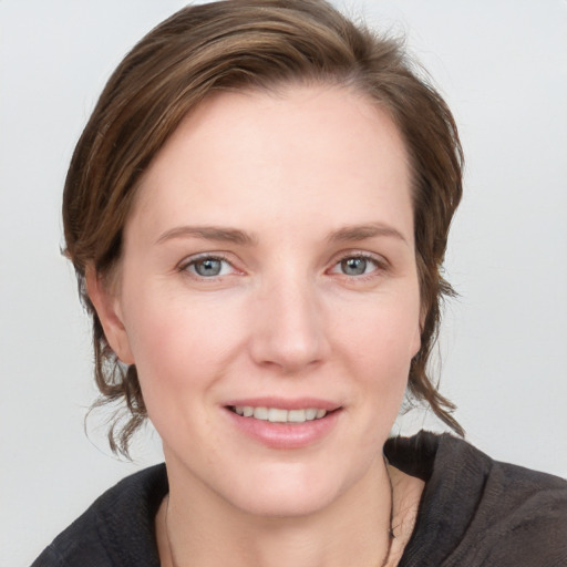 Joyful white young-adult female with medium  brown hair and grey eyes