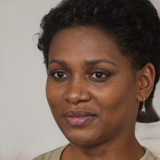 Joyful black young-adult female with short  black hair and brown eyes