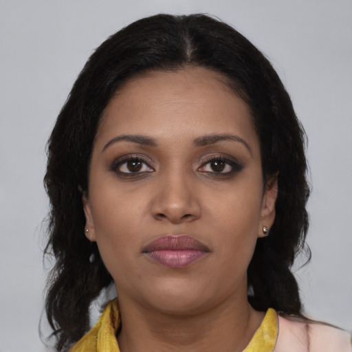Joyful black young-adult female with long  brown hair and brown eyes