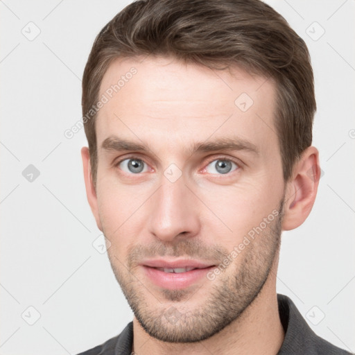 Joyful white young-adult male with short  brown hair and grey eyes