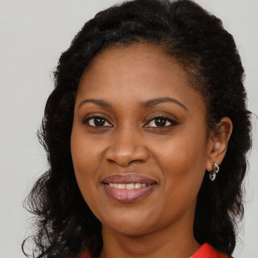 Joyful black young-adult female with long  brown hair and brown eyes
