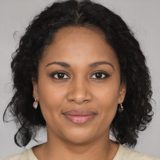 Joyful black young-adult female with long  brown hair and brown eyes