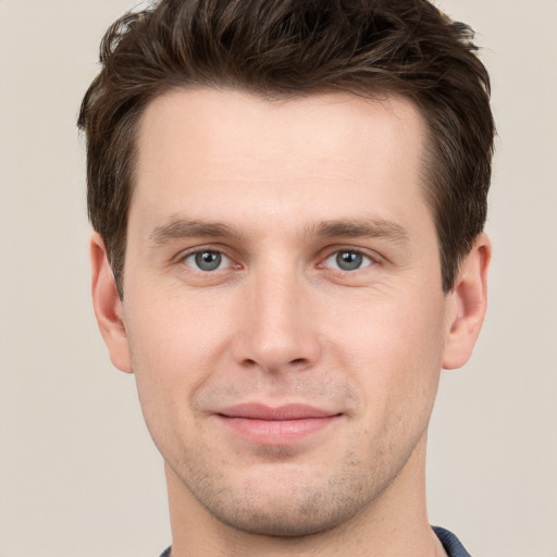 Joyful white young-adult male with short  brown hair and grey eyes