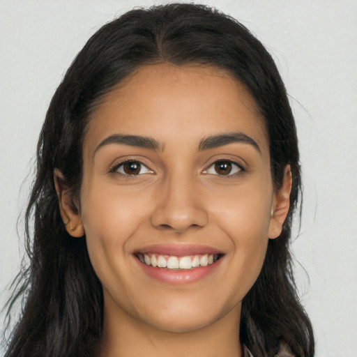 Joyful latino young-adult female with long  brown hair and brown eyes