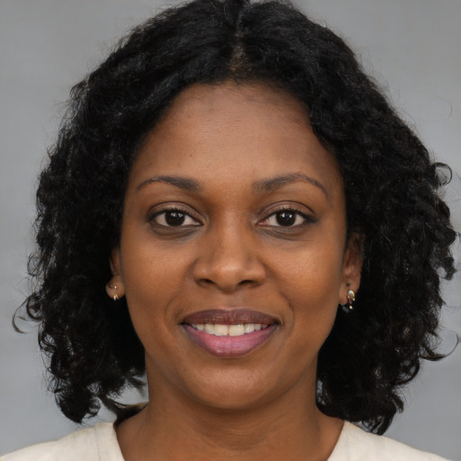 Joyful black young-adult female with long  brown hair and brown eyes