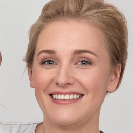 Joyful white young-adult female with short  brown hair and blue eyes