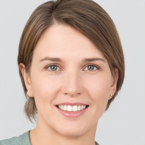 Joyful white young-adult female with medium  brown hair and grey eyes