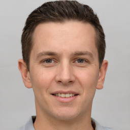 Joyful white young-adult male with short  brown hair and grey eyes