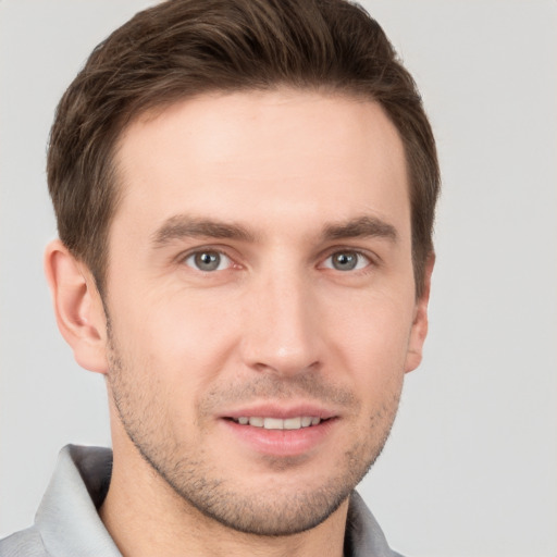 Joyful white young-adult male with short  brown hair and grey eyes