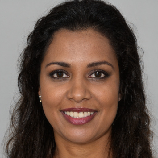 Joyful black young-adult female with long  brown hair and brown eyes