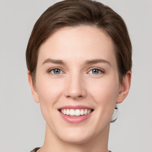 Joyful white young-adult female with short  brown hair and grey eyes