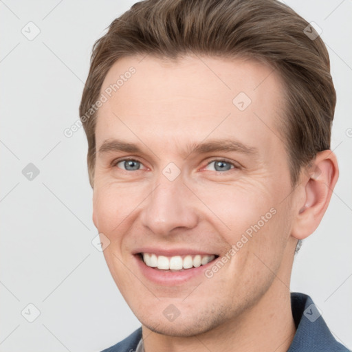 Joyful white young-adult male with short  brown hair and grey eyes