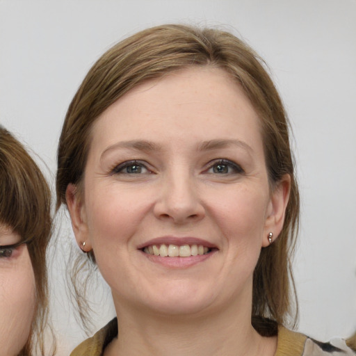 Joyful white young-adult female with medium  brown hair and grey eyes