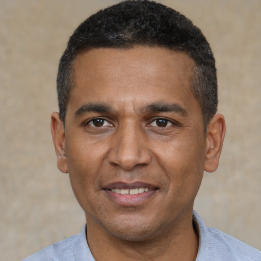 Joyful black adult male with short  black hair and brown eyes