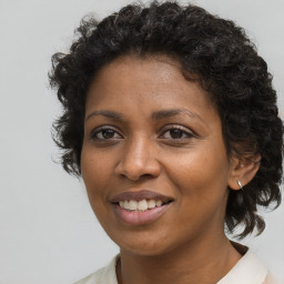 Joyful black young-adult female with long  brown hair and brown eyes