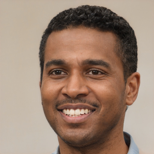 Joyful black young-adult male with short  black hair and brown eyes