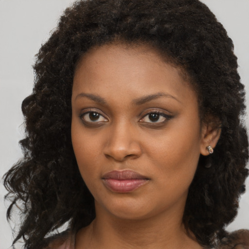 Joyful black young-adult female with long  brown hair and brown eyes