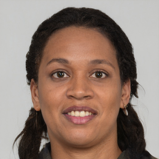 Joyful black adult female with long  brown hair and brown eyes