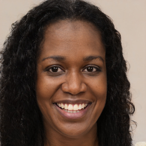 Joyful black young-adult female with long  brown hair and brown eyes