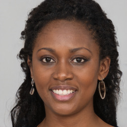 Joyful black young-adult female with long  brown hair and brown eyes