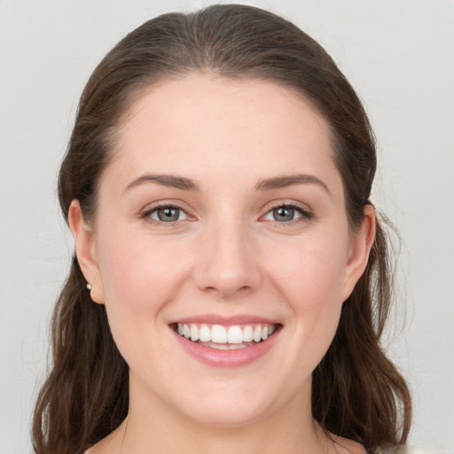 Joyful white young-adult female with long  brown hair and grey eyes