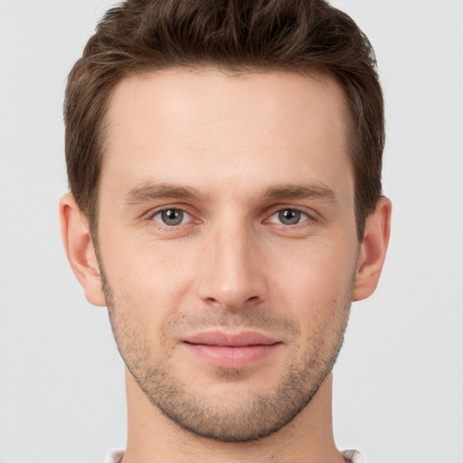 Joyful white young-adult male with short  brown hair and grey eyes